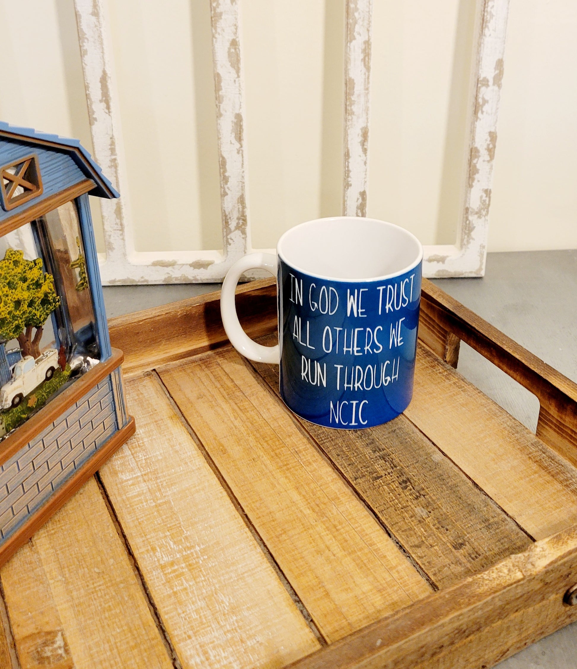 11 oz. coffee mug. Blue base that says "In God we trust. All others we run through NCIC"